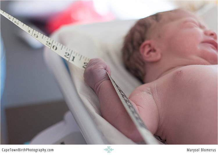 Newborn being measured during early care